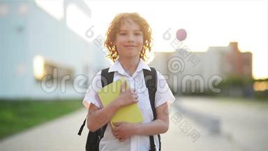 快乐可爱的聪明男孩手里拿着书包和书。 现代背包。 孩子准备回答。 第一次